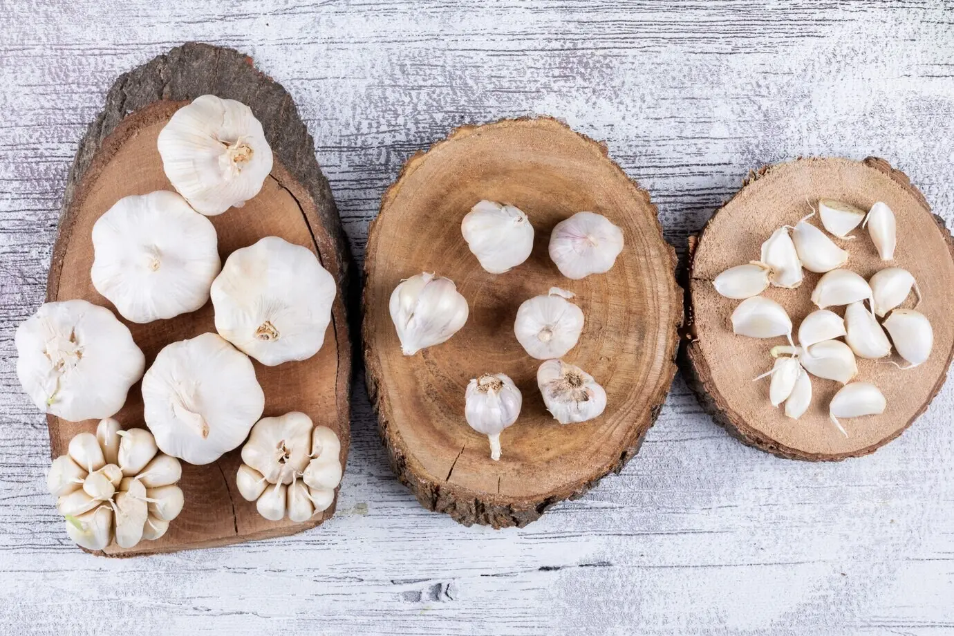 Knoblauchbündel auf Untersetzern auf einem hellen Holztisch. Ansicht von oben.